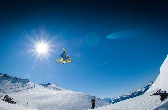 Snowboarder en el aire sobre montañas nevadas