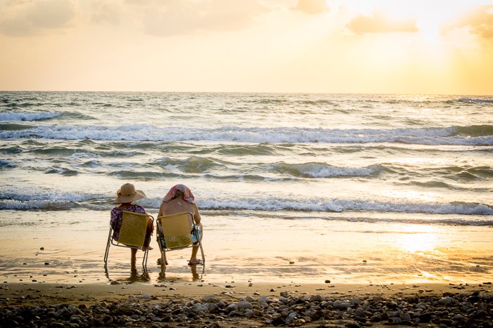 Una pareja de ancianos sentada junto al mar en sillas de camping amarillas