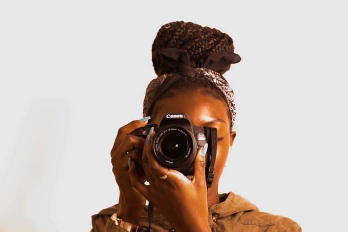Una mujer que sostiene una cámara con una lente de zoom