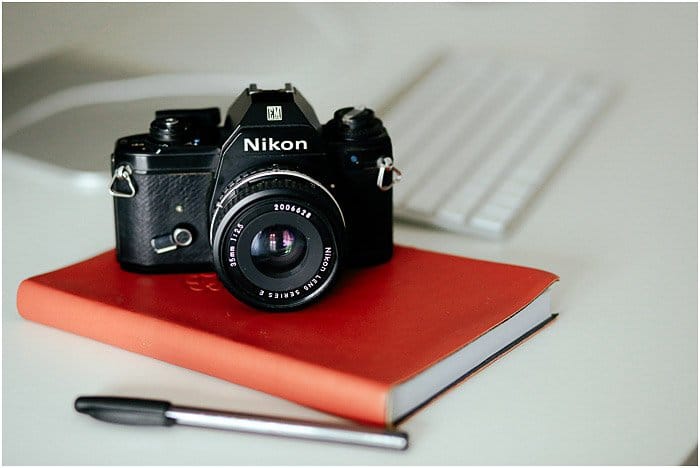una cámara Nikon descansando sobre un cuaderno rojo 